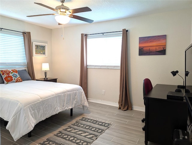 bedroom with multiple windows, baseboards, a ceiling fan, and wood tiled floor