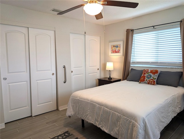 bedroom with ceiling fan, visible vents, and wood finish floors