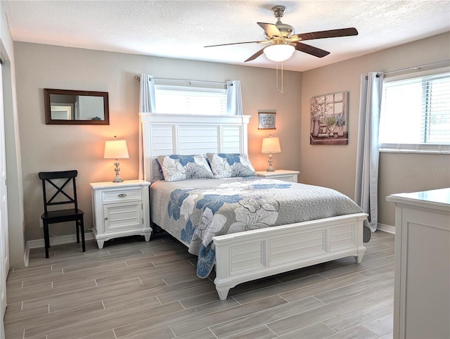 bedroom with a textured ceiling, baseboards, wood finish floors, and a ceiling fan