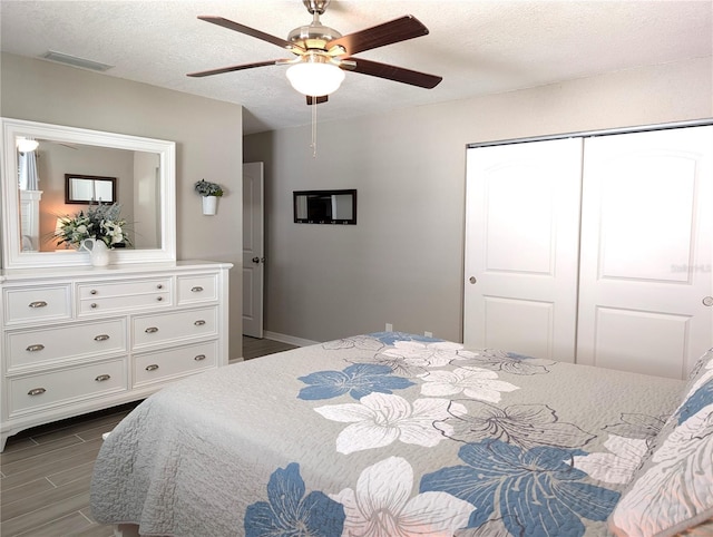 bedroom with a closet, visible vents, a textured ceiling, and wood tiled floor