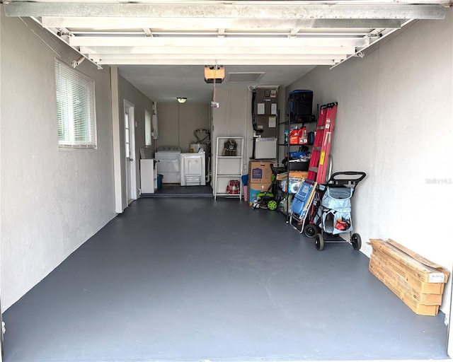 garage featuring heating unit, independent washer and dryer, a garage door opener, and a textured wall