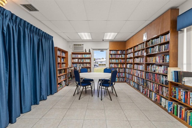 dining room featuring visible vents, built in features, a drop ceiling, a wall unit AC, and light tile patterned floors