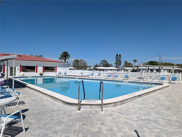 community pool with a patio and fence