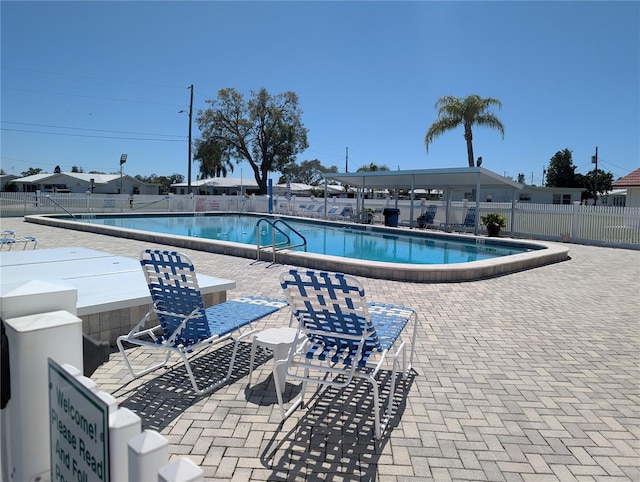 pool with a patio area and fence