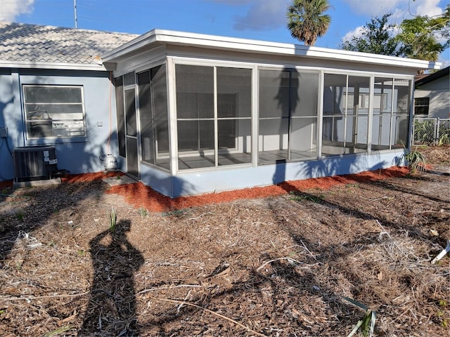 rear view of property featuring a sunroom and central air condition unit