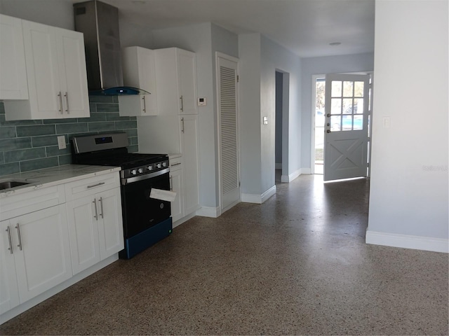 kitchen featuring sink, stainless steel stove, white cabinetry, backsplash, and wall chimney exhaust hood