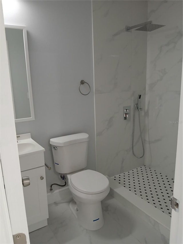 bathroom with tiled shower, vanity, and toilet