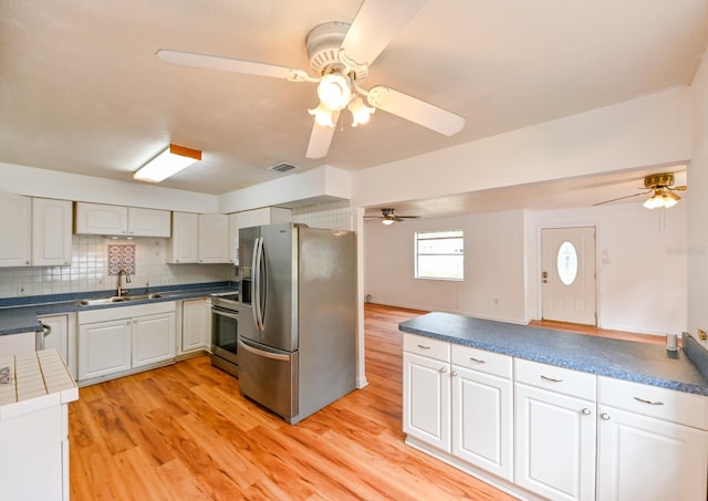 kitchen with light wood finished floors, tasteful backsplash, visible vents, appliances with stainless steel finishes, and a sink