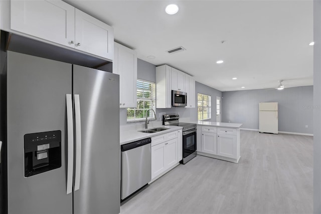 kitchen featuring kitchen peninsula, light hardwood / wood-style floors, sink, appliances with stainless steel finishes, and white cabinets