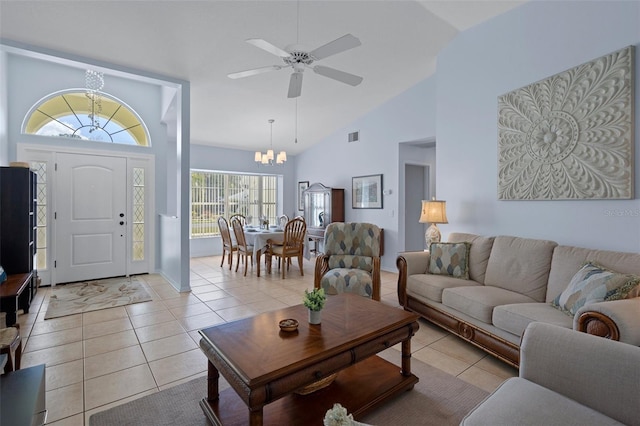 tiled living room with ceiling fan with notable chandelier and high vaulted ceiling