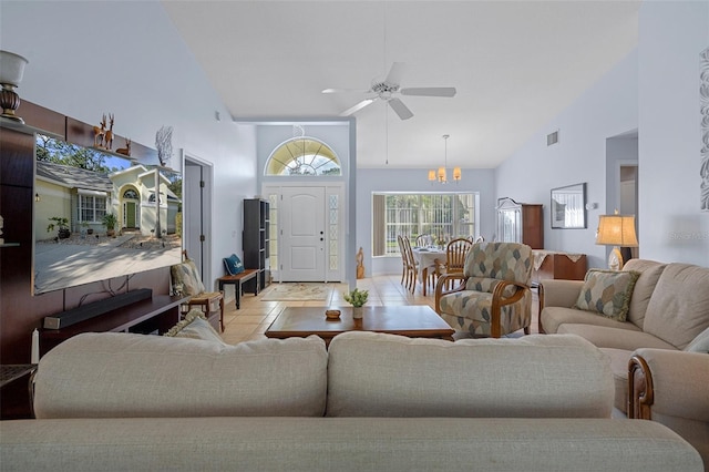 living room featuring light tile patterned flooring, ceiling fan with notable chandelier, and high vaulted ceiling