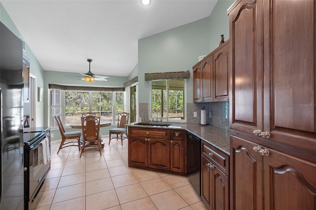 kitchen with lofted ceiling, light tile patterned floors, backsplash, black appliances, and dark stone counters