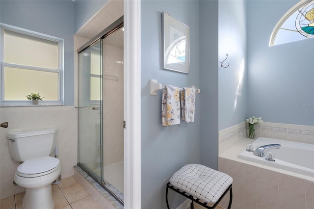 bathroom featuring toilet, independent shower and bath, tile patterned flooring, and tile walls