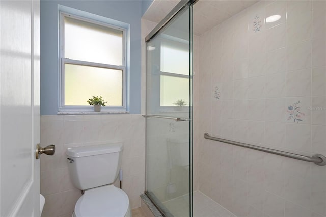 bathroom with a shower with door, tile walls, and toilet