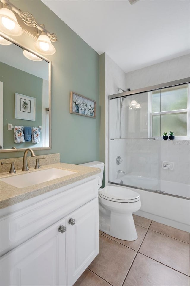 full bathroom featuring toilet, tile patterned floors, bath / shower combo with glass door, and vanity