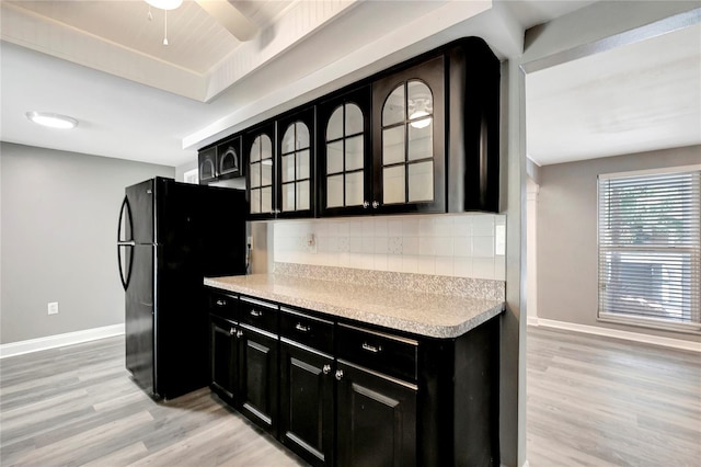 kitchen with tasteful backsplash, light hardwood / wood-style flooring, ceiling fan, and black fridge