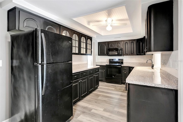 kitchen featuring sink, ceiling fan, black appliances, a raised ceiling, and light wood-type flooring