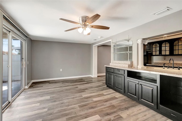 kitchen featuring tasteful backsplash, sink, ceiling fan, light stone counters, and light hardwood / wood-style floors