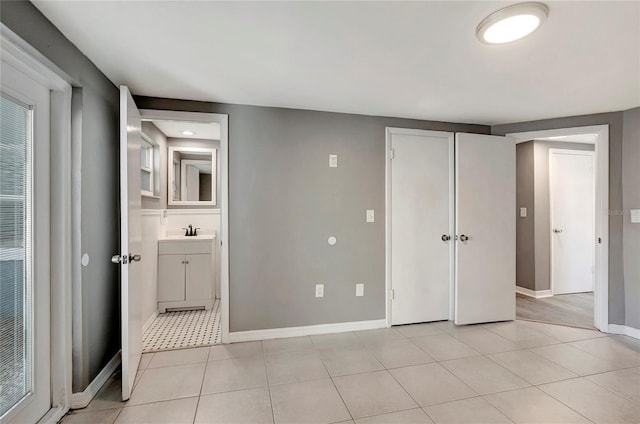 unfurnished bedroom with light tile patterned floors, a closet, and sink