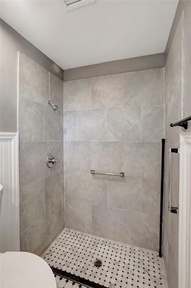 bathroom featuring tiled shower and toilet