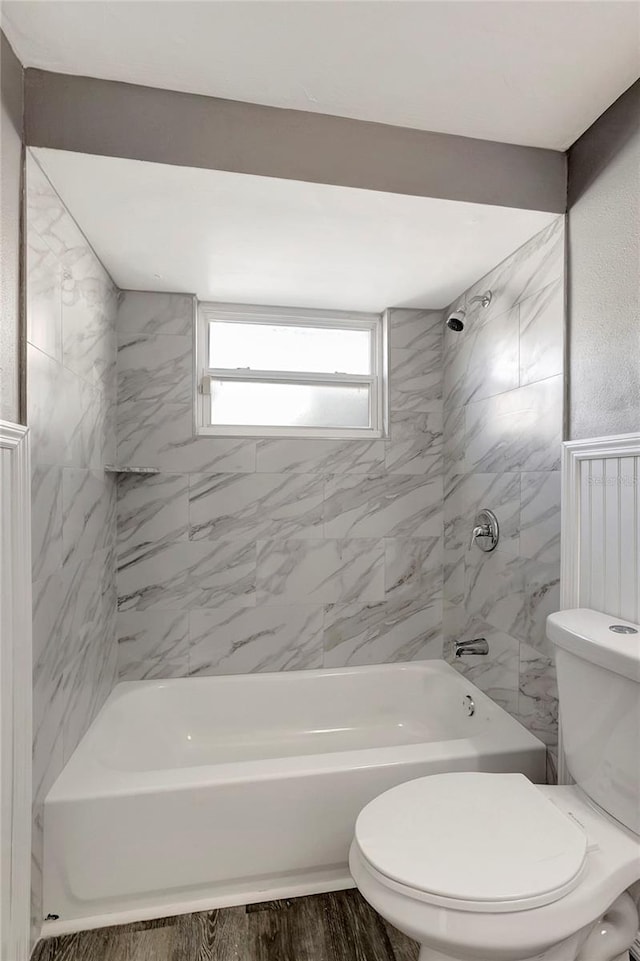 bathroom with hardwood / wood-style flooring, toilet, and tiled shower / bath combo