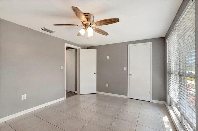 tiled spare room with ceiling fan