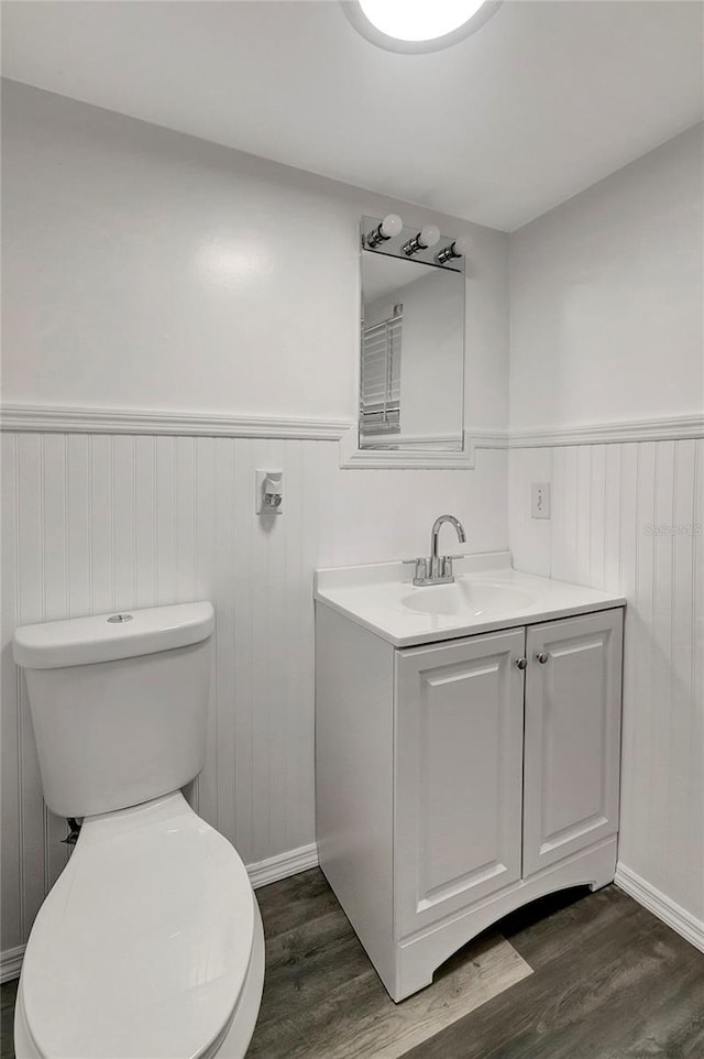 bathroom with hardwood / wood-style flooring, vanity, and toilet