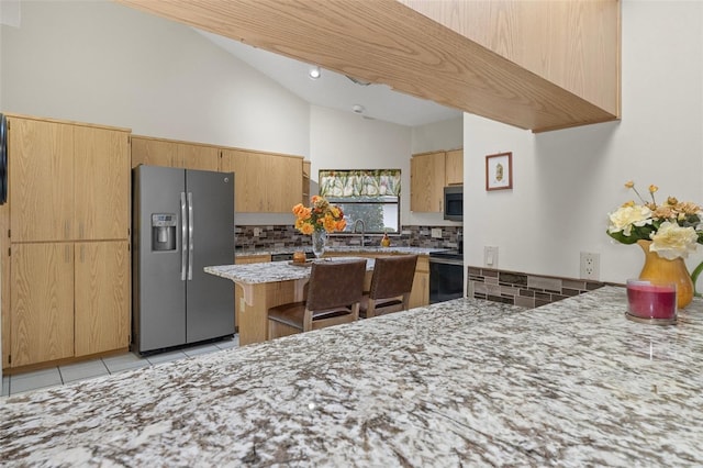 kitchen featuring vaulted ceiling, tasteful backsplash, light tile patterned floors, kitchen peninsula, and stainless steel appliances