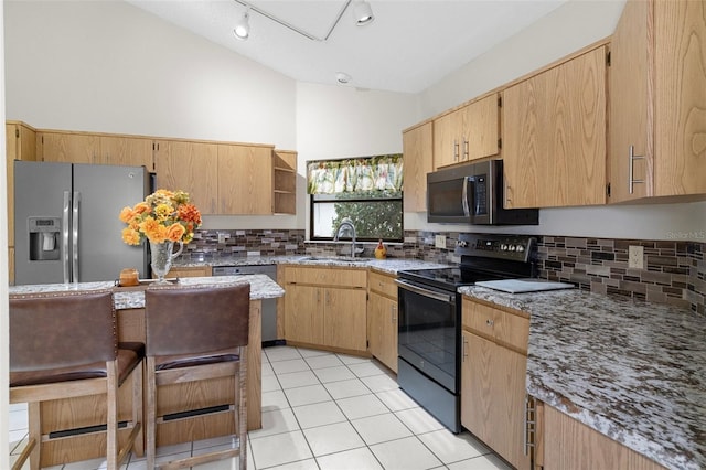 kitchen featuring light tile patterned flooring, lofted ceiling, light brown cabinetry, sink, and stainless steel appliances