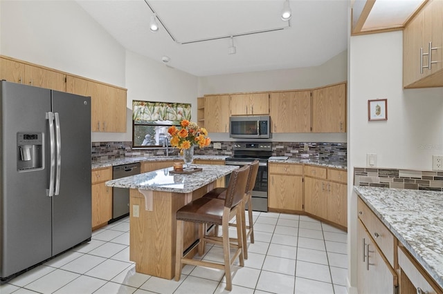 kitchen with stainless steel appliances, a center island, light tile patterned floors, and a kitchen breakfast bar