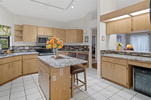 kitchen featuring light tile patterned floors, sink, appliances with stainless steel finishes, a kitchen island, and a kitchen bar