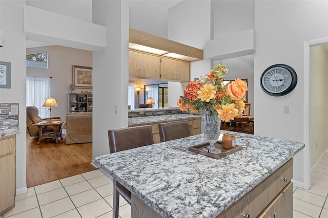 kitchen featuring a high ceiling, light tile patterned flooring, and light stone countertops