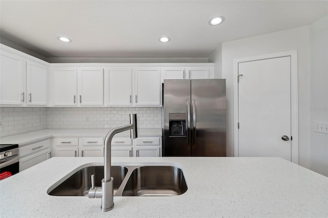 kitchen with sink, white cabinetry, backsplash, light stone counters, and stainless steel fridge with ice dispenser