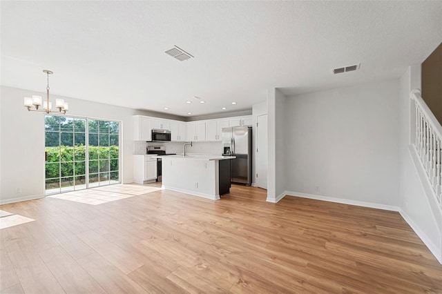 unfurnished living room featuring sink, a notable chandelier, and light hardwood / wood-style floors