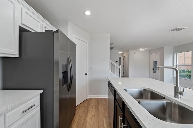 kitchen featuring appliances with stainless steel finishes, white cabinetry, sink, light stone counters, and light wood-type flooring