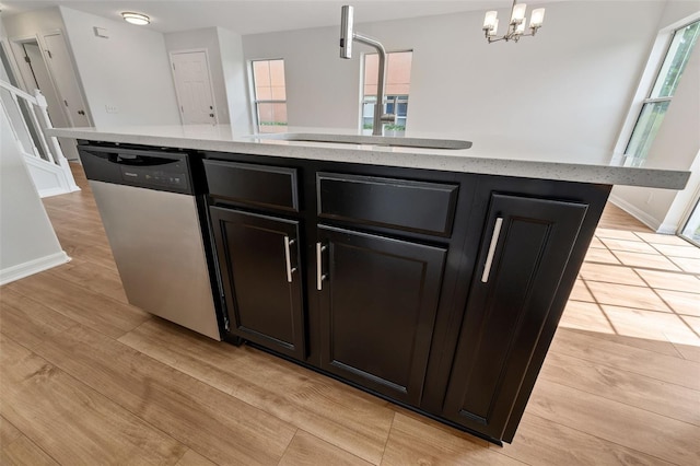 kitchen featuring decorative light fixtures, sink, a kitchen island with sink, stainless steel dishwasher, and light hardwood / wood-style floors