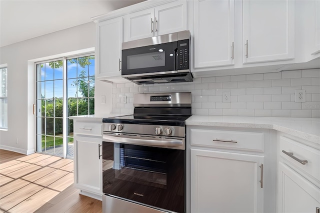 kitchen featuring light hardwood / wood-style flooring, backsplash, stainless steel appliances, light stone counters, and white cabinets