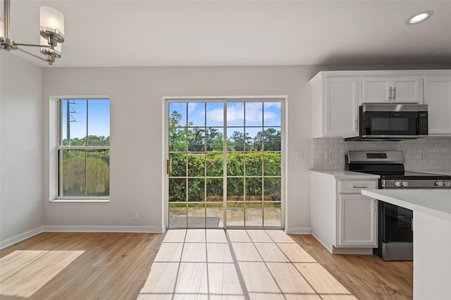 kitchen featuring white cabinetry, tasteful backsplash, stainless steel appliances, and light wood-type flooring