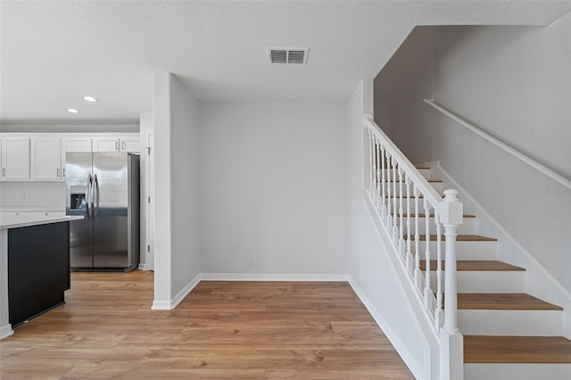 stairway with hardwood / wood-style flooring and a textured ceiling