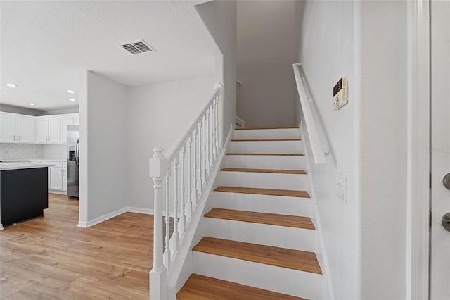 stairway featuring wood-type flooring and a textured ceiling