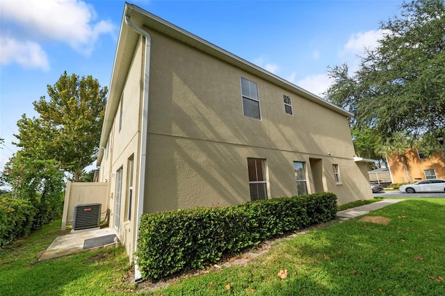 view of property exterior featuring central air condition unit and a lawn