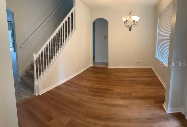 interior space featuring baseboards, stairs, arched walkways, and dark wood-style flooring