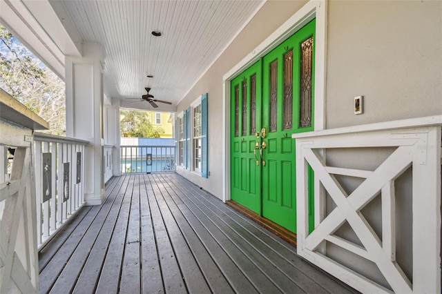 wooden terrace featuring covered porch and a ceiling fan