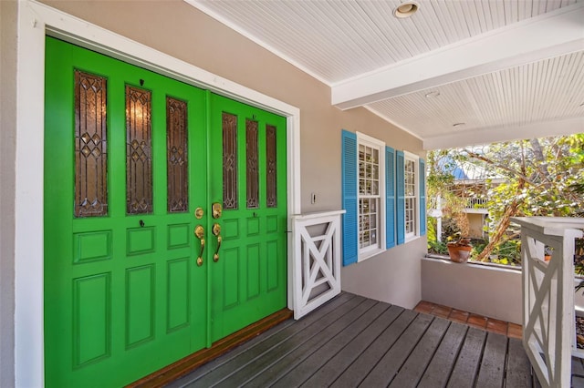 doorway to property featuring covered porch and stucco siding