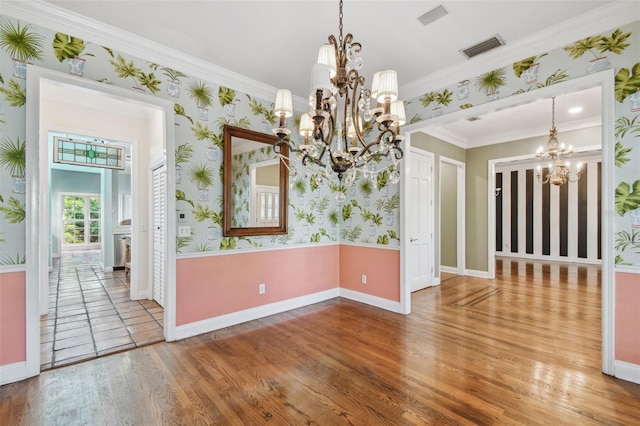 unfurnished room with wood finished floors, visible vents, an inviting chandelier, and wallpapered walls