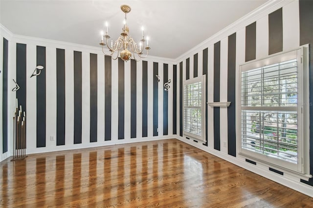 empty room with ornamental molding, a wealth of natural light, wood finished floors, and wallpapered walls