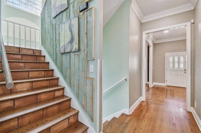 staircase featuring crown molding, baseboards, and wood finished floors