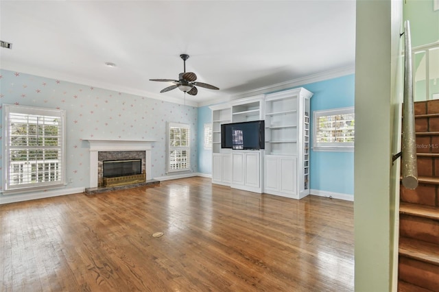 unfurnished living room featuring hardwood / wood-style flooring, visible vents, baseboards, wallpapered walls, and crown molding