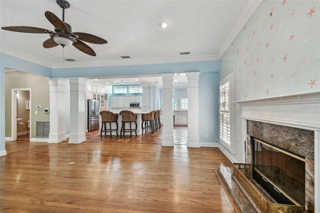 living room featuring wallpapered walls, decorative columns, and a fireplace