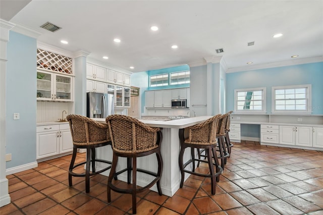 kitchen featuring crown molding, built in desk, a breakfast bar area, recessed lighting, and appliances with stainless steel finishes